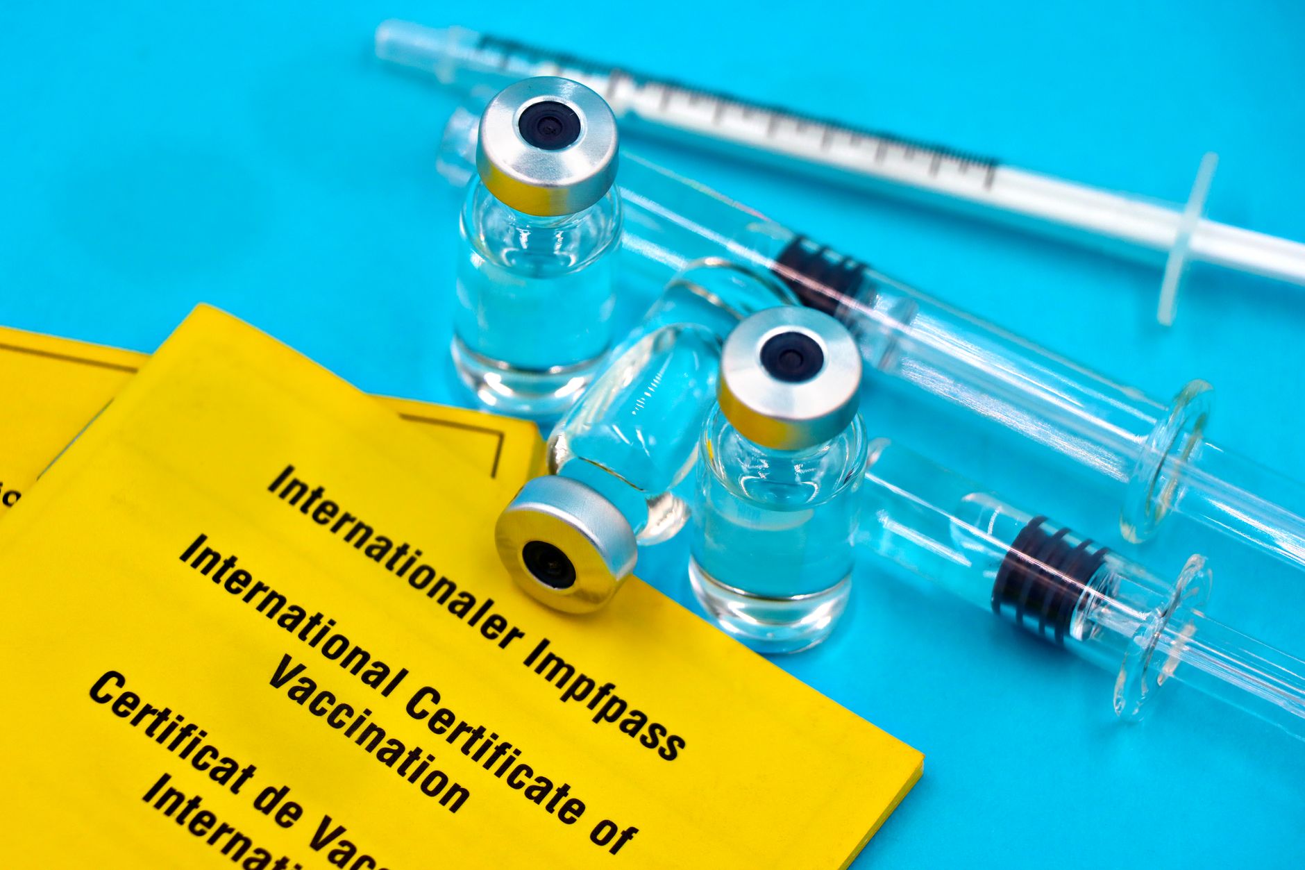 Close-up of vaccination certificates and vials on a blue background.