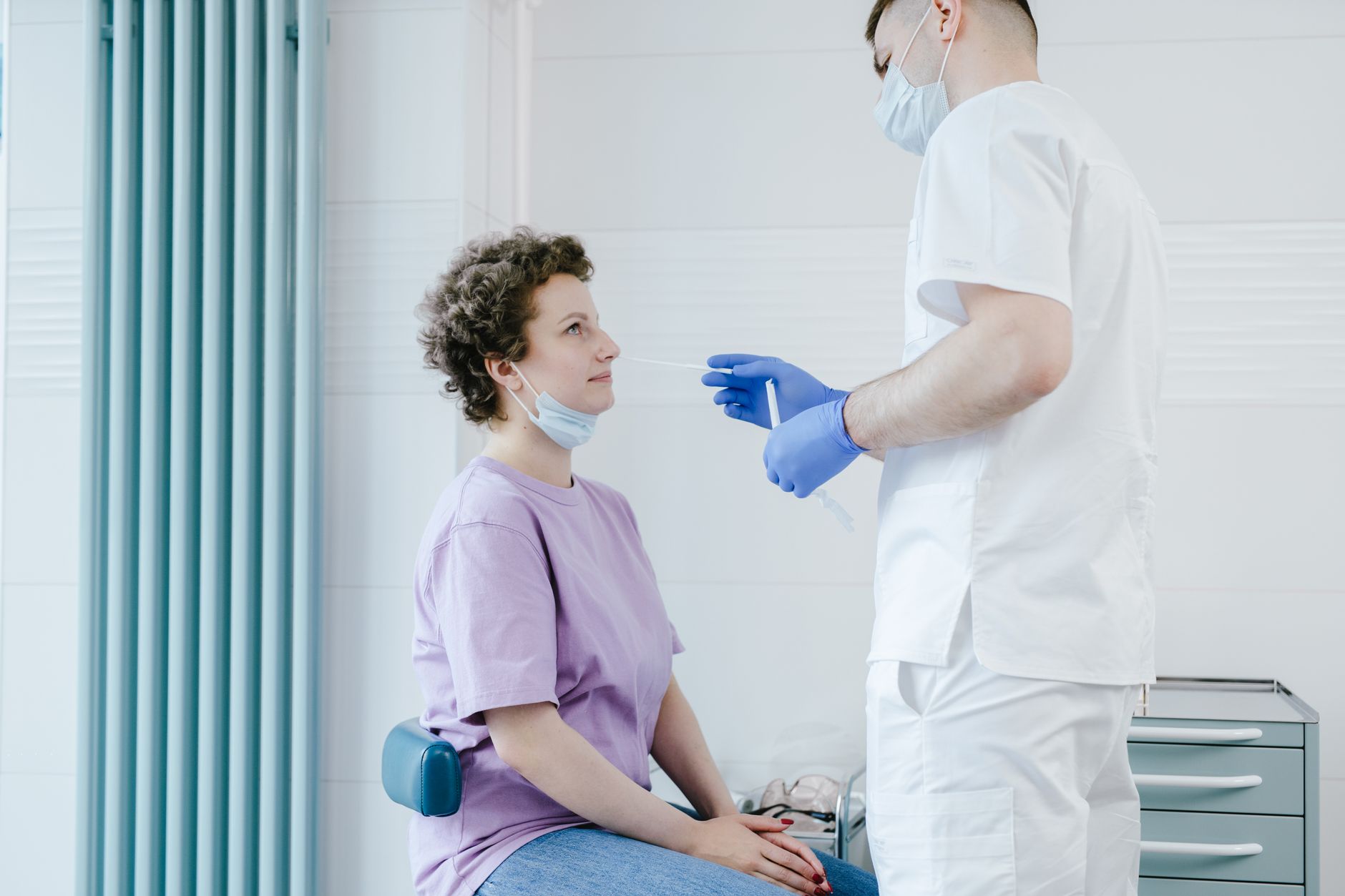Clinician in mask using a flexible scope on a patient in a clinic.