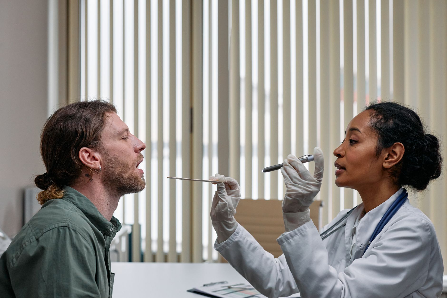 A doctor performs flexible transnasal endoscopy on a patient in a clinic.