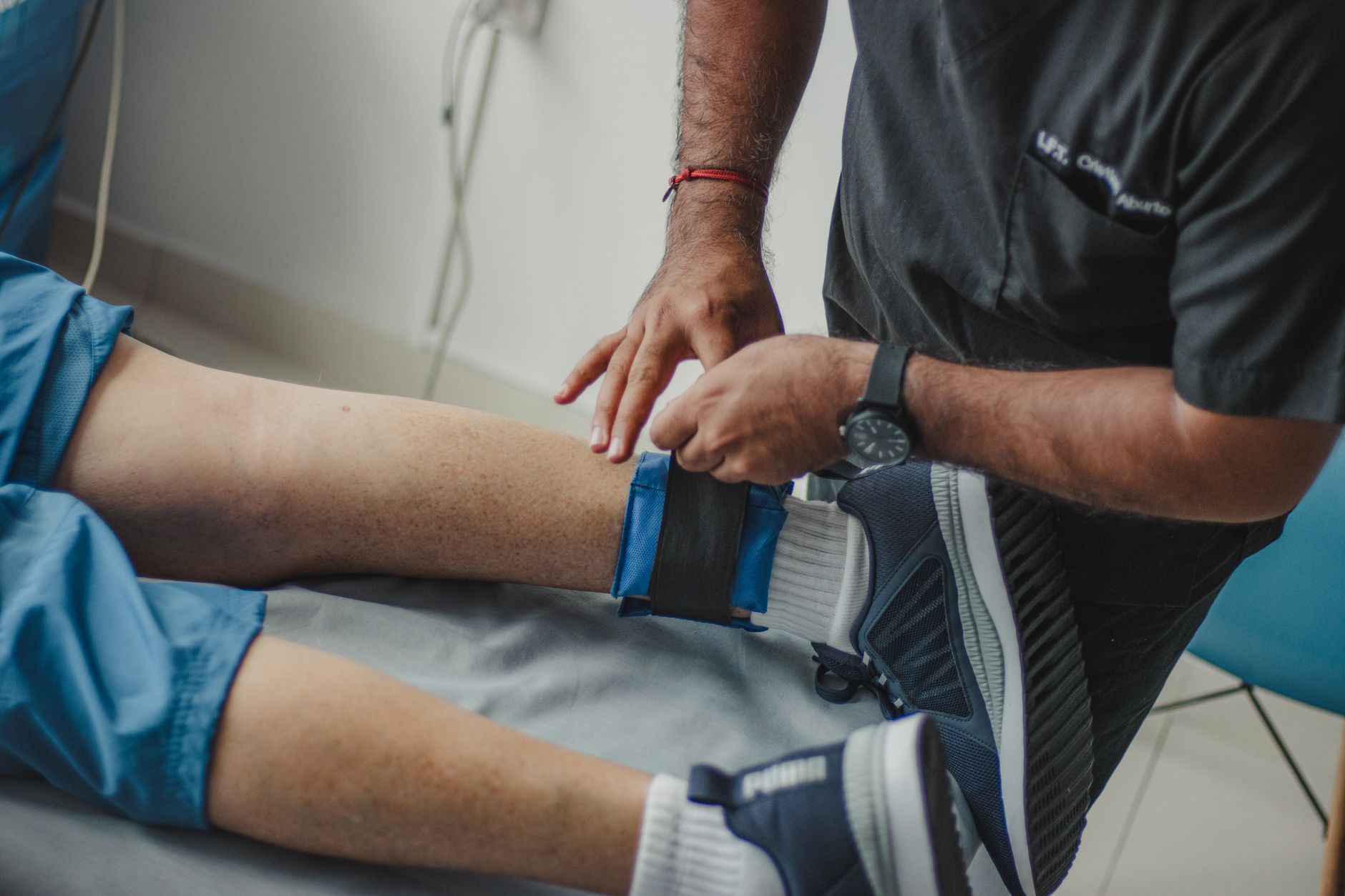 A physiotherapist applying a support band on a senior patient's leg in a rehab center.
