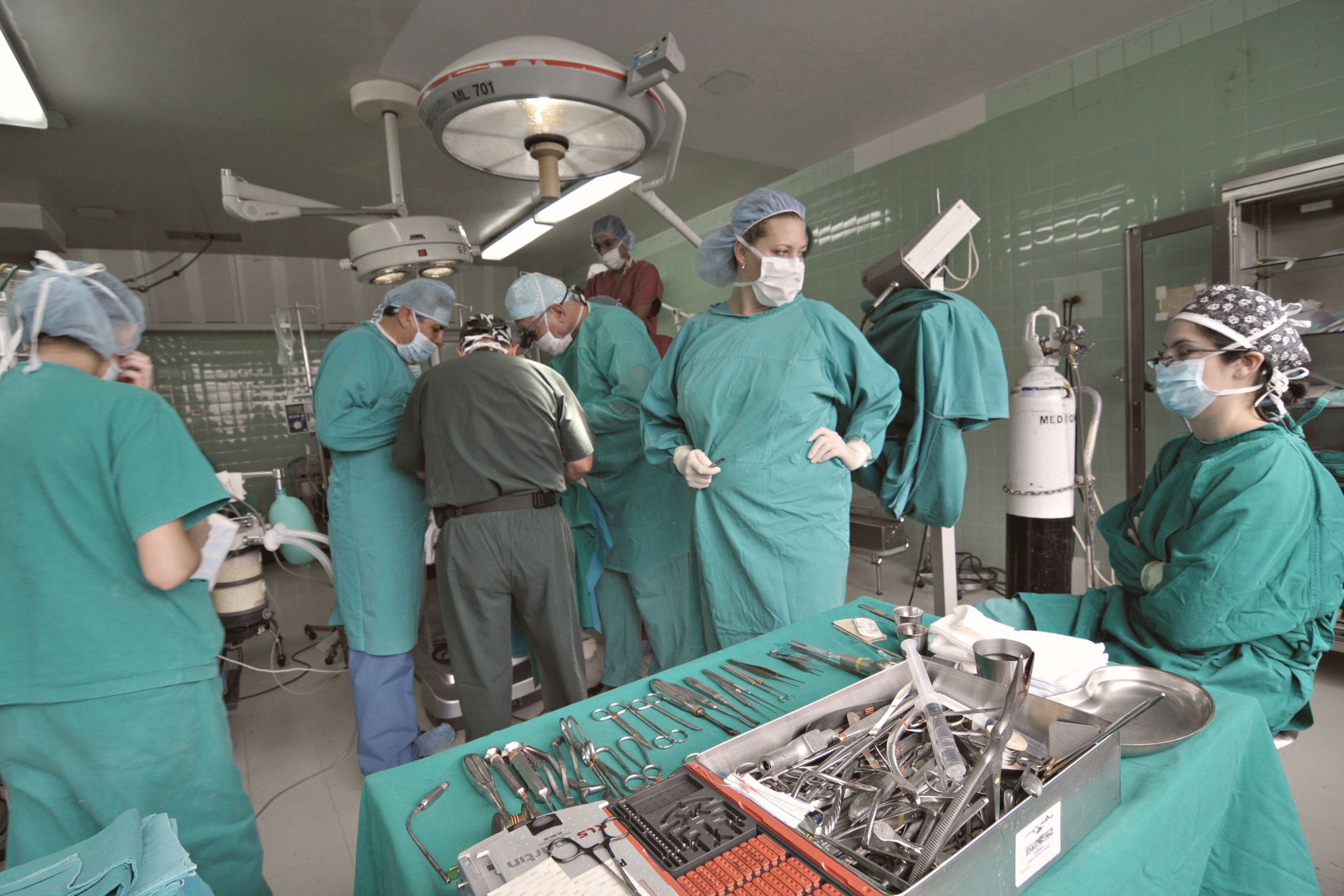 A surgical team in green scrubs actively engaged in a procedure in a modern operating room.