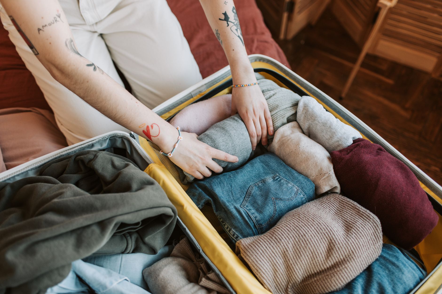 A person packing a suitcase with layered clothing essentials for a winter medical trip.