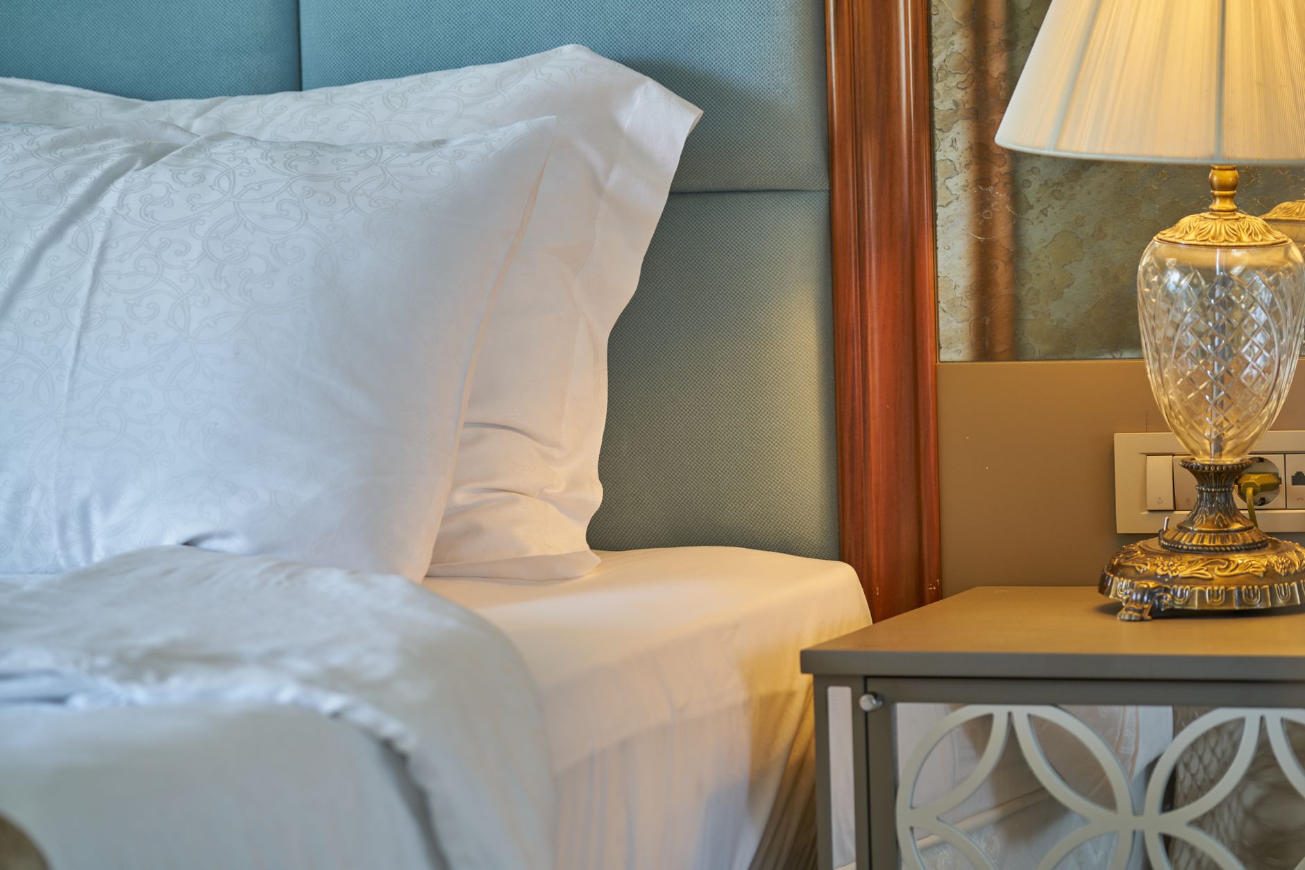 A well-decorated hotel room in Istanbul featuring plush pillows, a bedside lamp, and soft lighting.