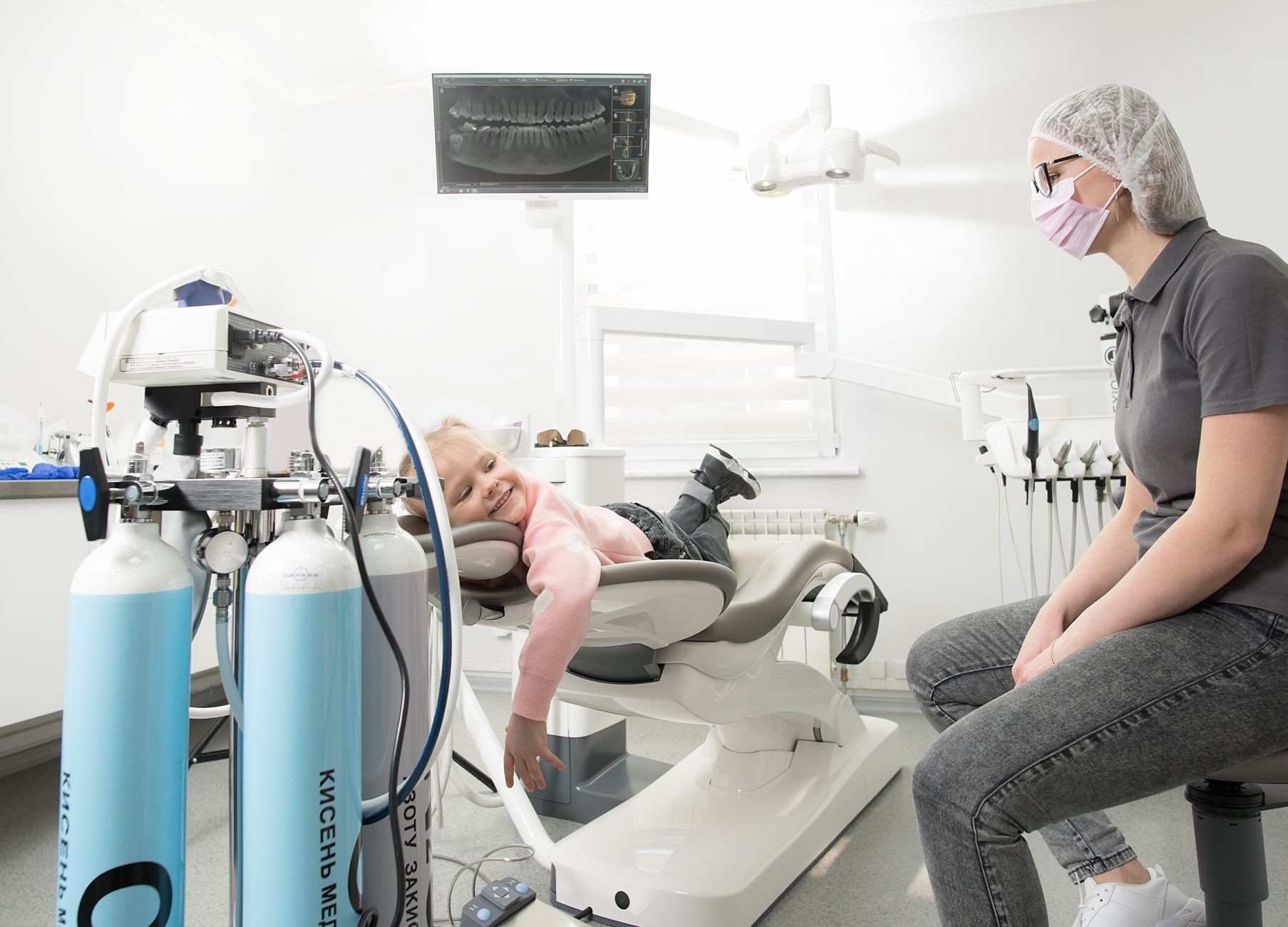 A young girl under conscious sedation in a dental chair with monitoring equipment.