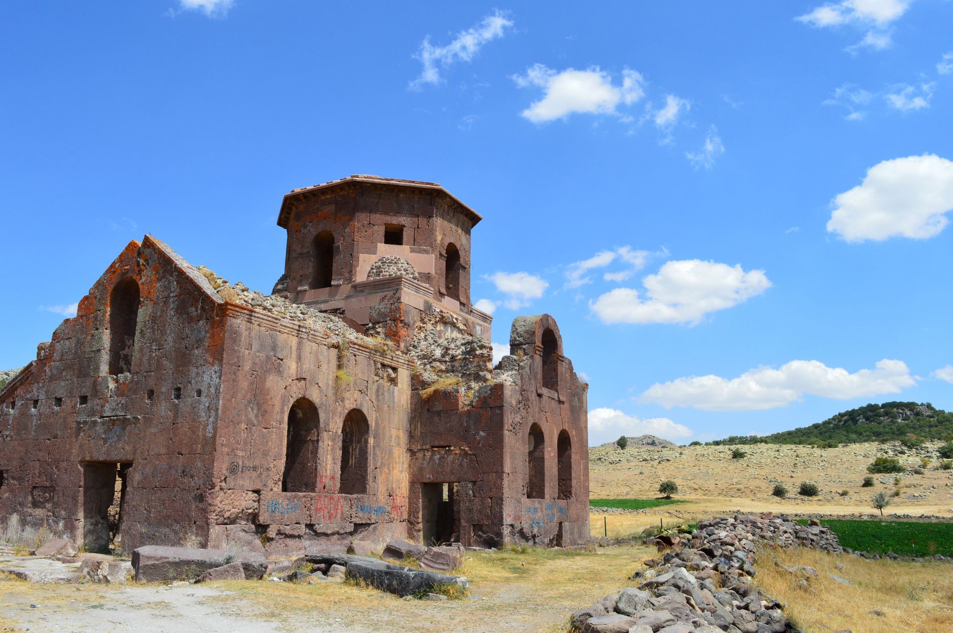 Close-up view of weathered church ruins featuring arched windows and a blue sky.